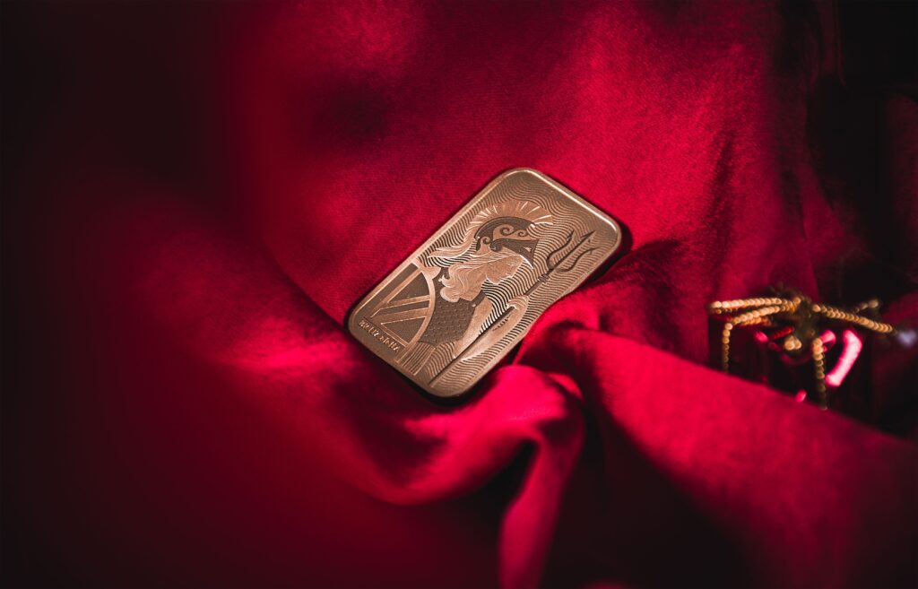 A beautifully detailed gold bar resting on luxurious red velvet, symbolizing wealth and elegance.